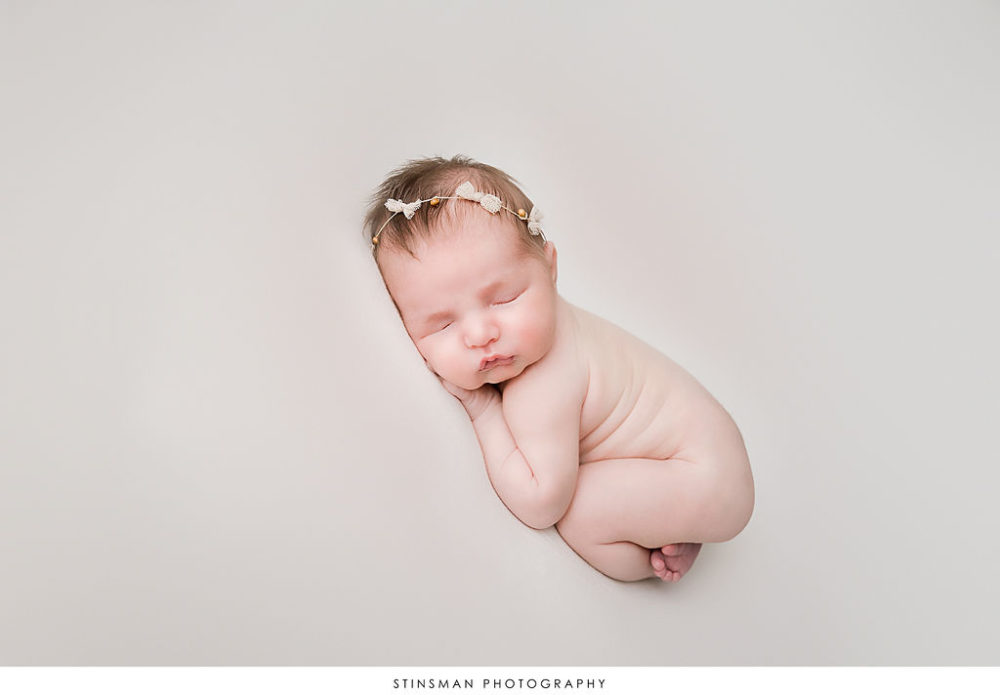 newborn girl sleeping peacefully in fetal position for first in-studio photo shoot in South jersey