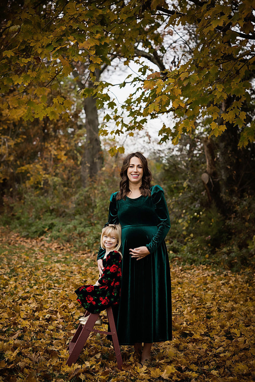 8 month pregnant mom with daughter posing in woodsy area for maternity pictures in Central New Jersey