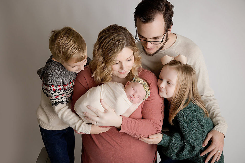 Mom, dad, brother and sister looking lovingly at newborn baby girl for newborn photoshoot in New Jersey