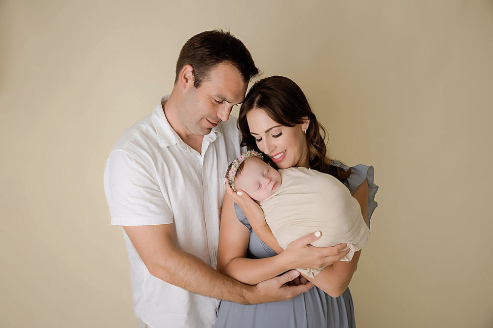 Mom and dad holding baby girl for in-studio newborn photoshoot in south New Jersey.