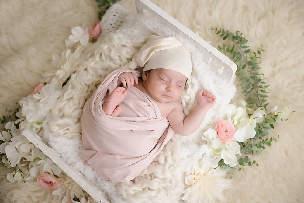 Baby girl in infant crib for newborn session in Central New Jersey.