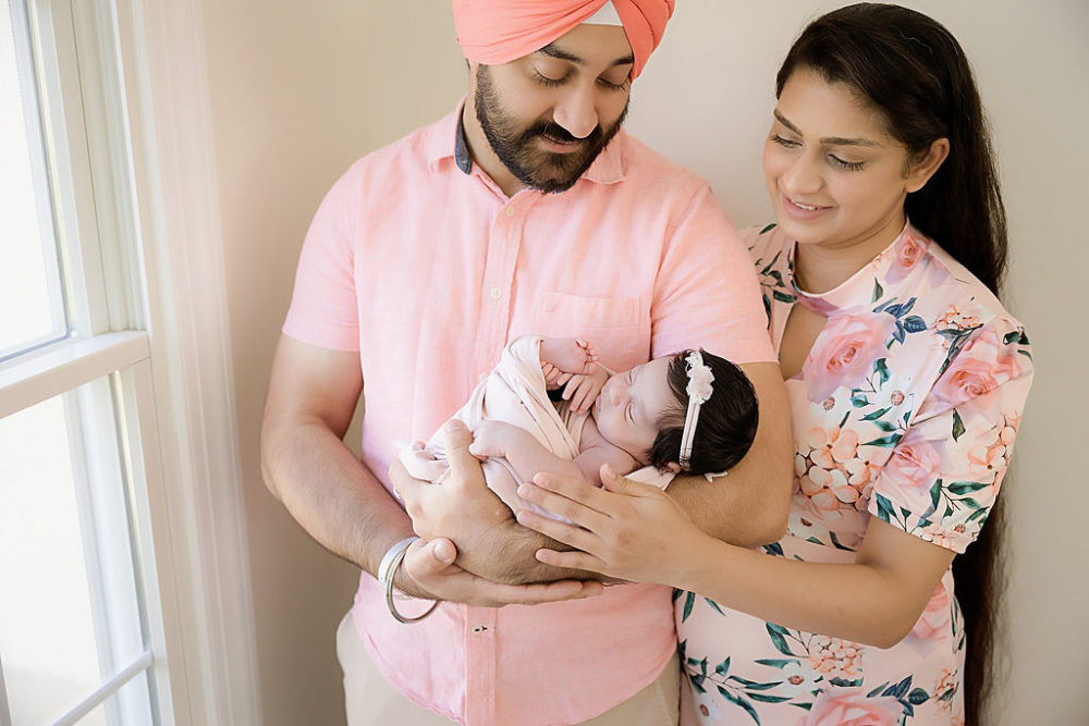 Young couple holding baby girl for in-home newborn photography session in South New Jersey.