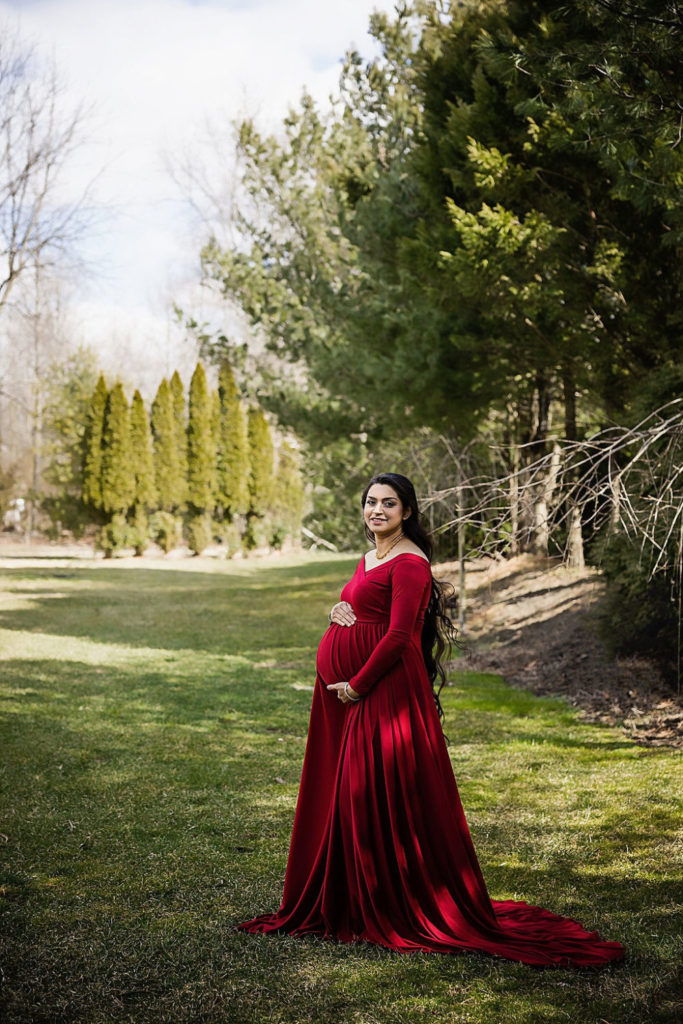 Mom wearing dress, smiling and holding belly for her in-home maternity photoshoot in Voorhees, New Jersey.