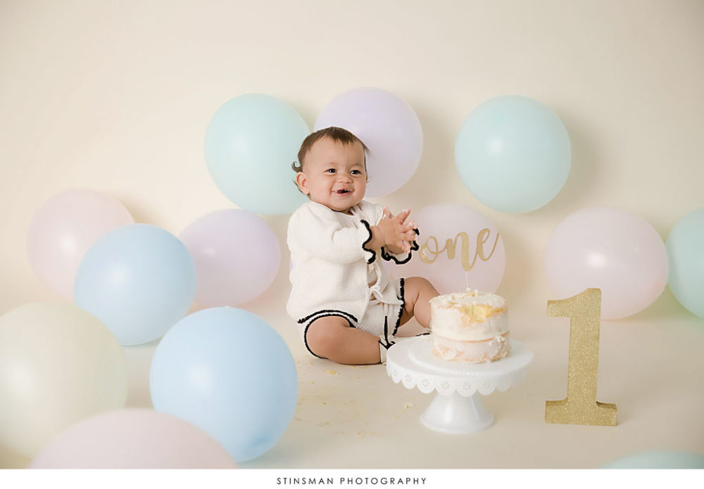 Smiling one year old girl with naked smash cake and number one for her first birthday pics in Atlantic City, New Jersey.