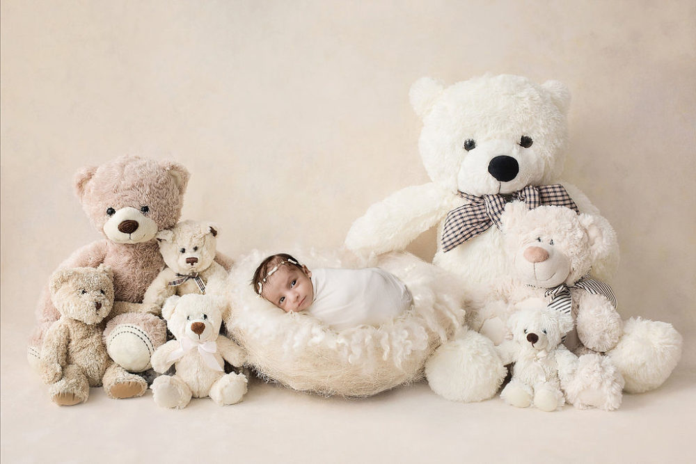 Newborn girl swaddled with bear backdrop for her in-studio newborn session in Pemberton, New Jersey.