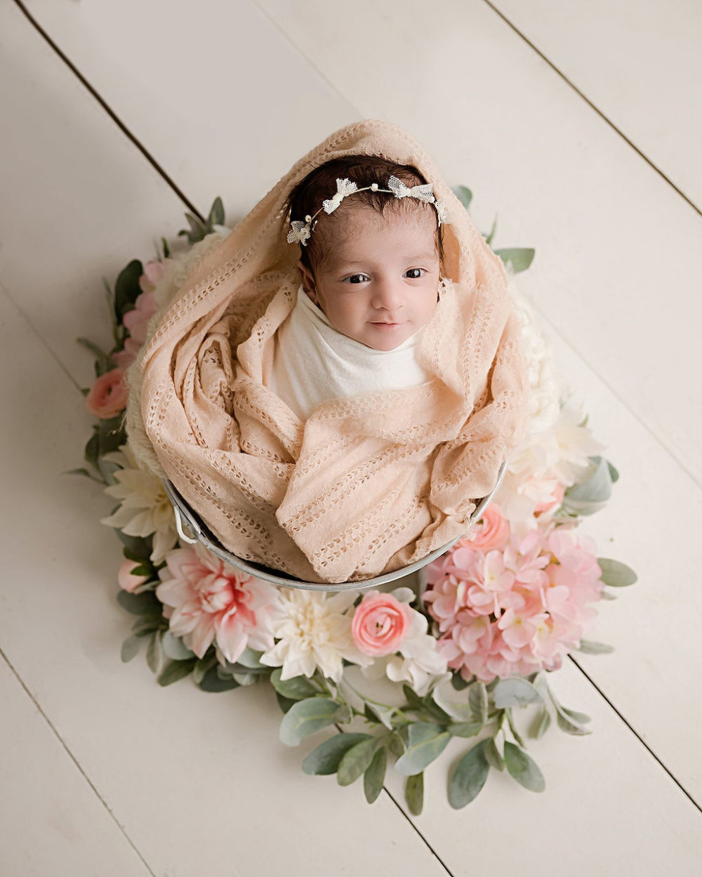 Newborn girl awake and smiling in bucker prop for her first in-studio newborn session in Vineland, New Jersey.