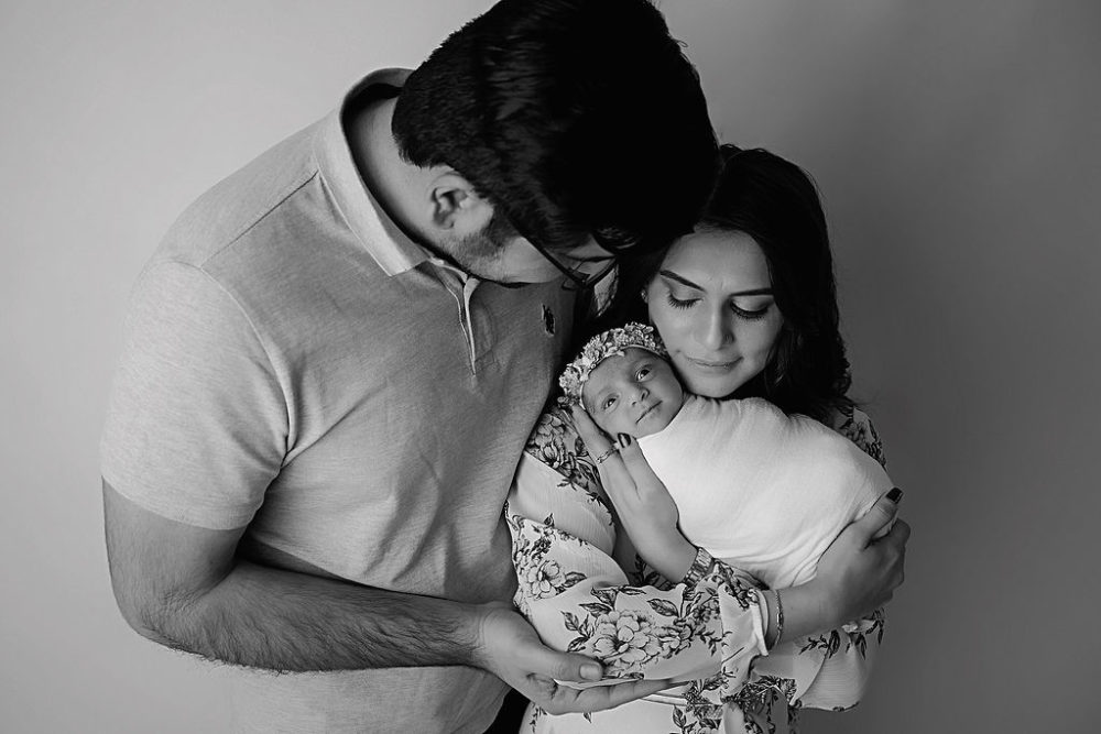 Mom and dad cradling baby girl for her in-studio newborn session in Freehold, New Jersey.