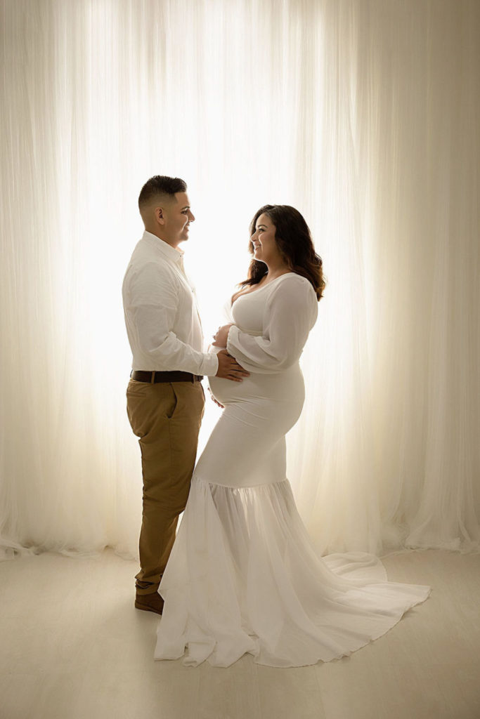 Mom and Dad looking at each other for her in-studio maternity session in Freehold, New Jersey.
