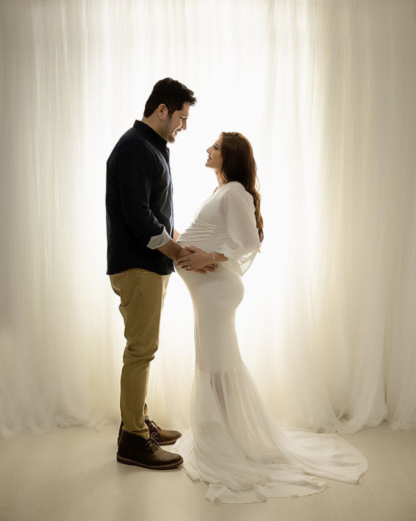 New parents facing each other and her holding belly for her luxurious maternity session in Camden, New Jersey.