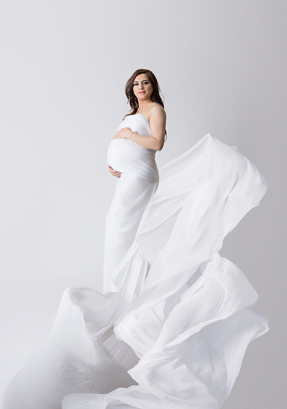 Mom holding belly wearing warp dress for her luxurious maternity and in-studio newborn sessions in Southampton, New Jersey.