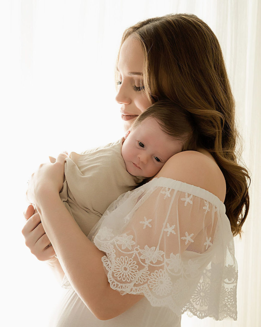 New mom wearing dress holding baby in wrap for his light and simple newborn session in Voorhees, New Jersey.