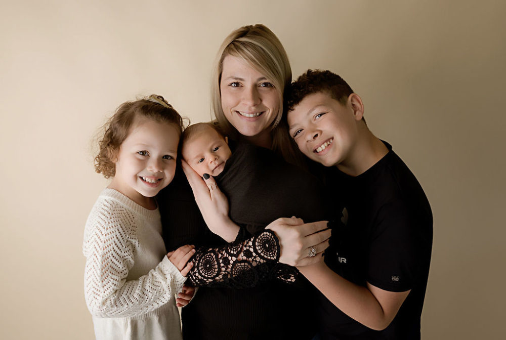 Smiling mom and her three children for her black-and-white maternity and newborn session in Trenton, New Jersey.