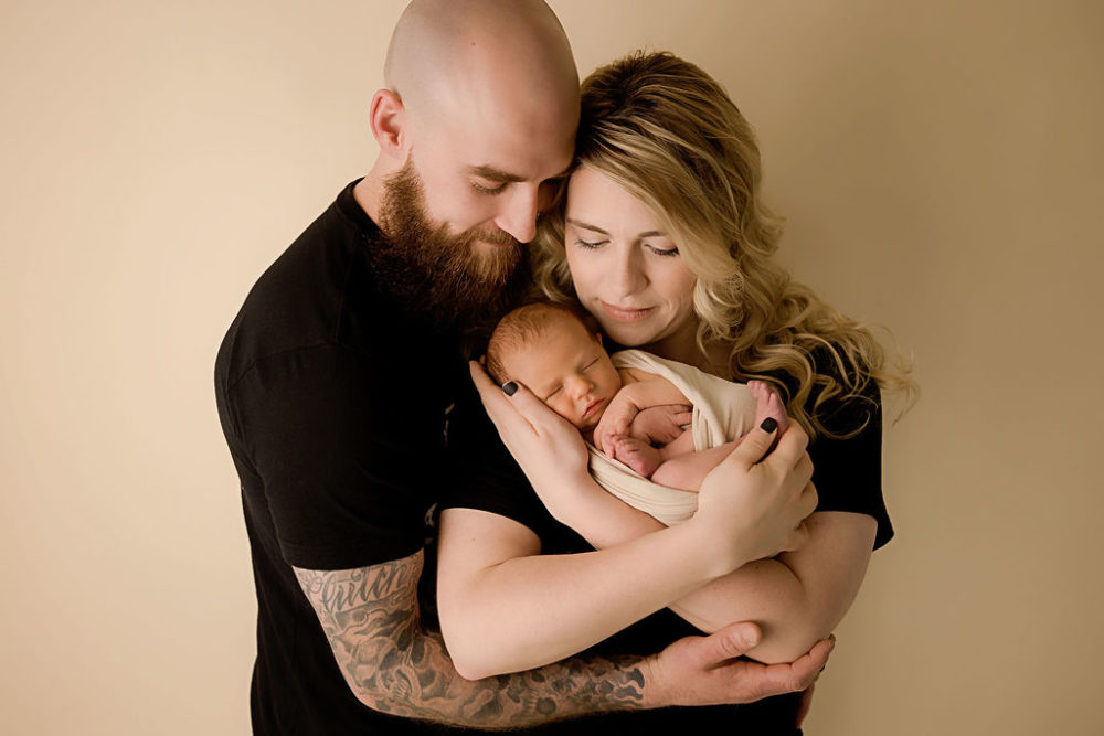mom and dad holding baby boy for her black-and-white maternity and newborn session in Monroe, New Jersey.