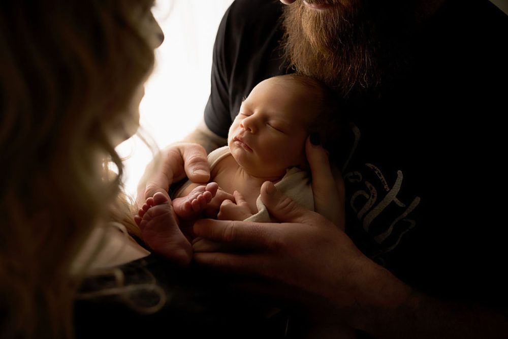 Newborn boy bring held by mom and dad for infant photography in Stafford, New Jersey.