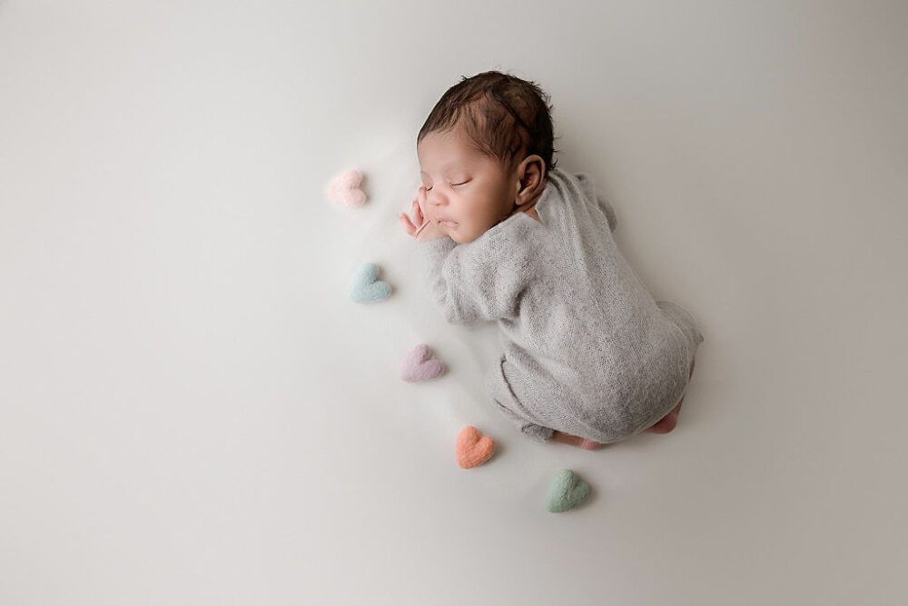Baby boy sleeping on tummy with felt hearts photography props for his warm and earthy newborn session in Pemberton, New Jersey.