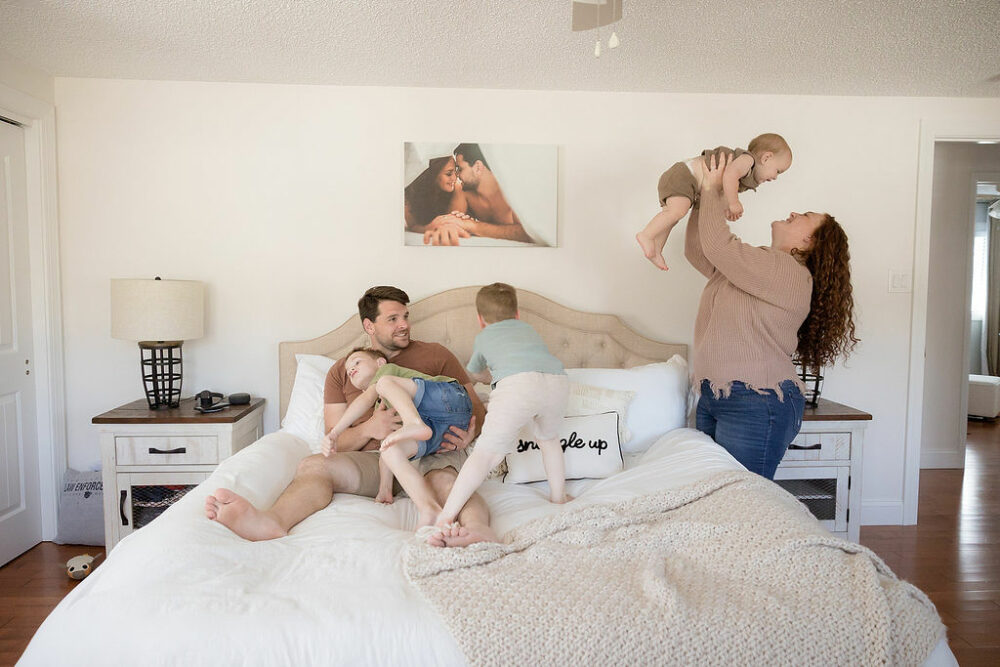 Candid picture of mom and dad playing with their sons for their in-home lifestyle family session in Burlington, New Jersey.