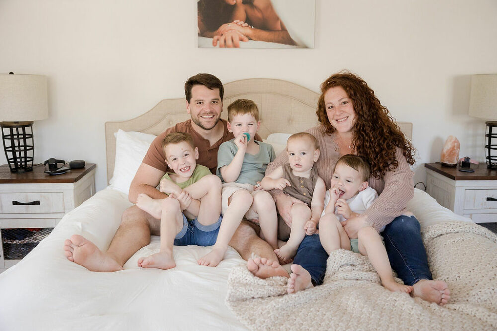 Mom and dad with their four boys snuggling on bed for their in-home lifestyle family session in Ocean City, New Jersey.