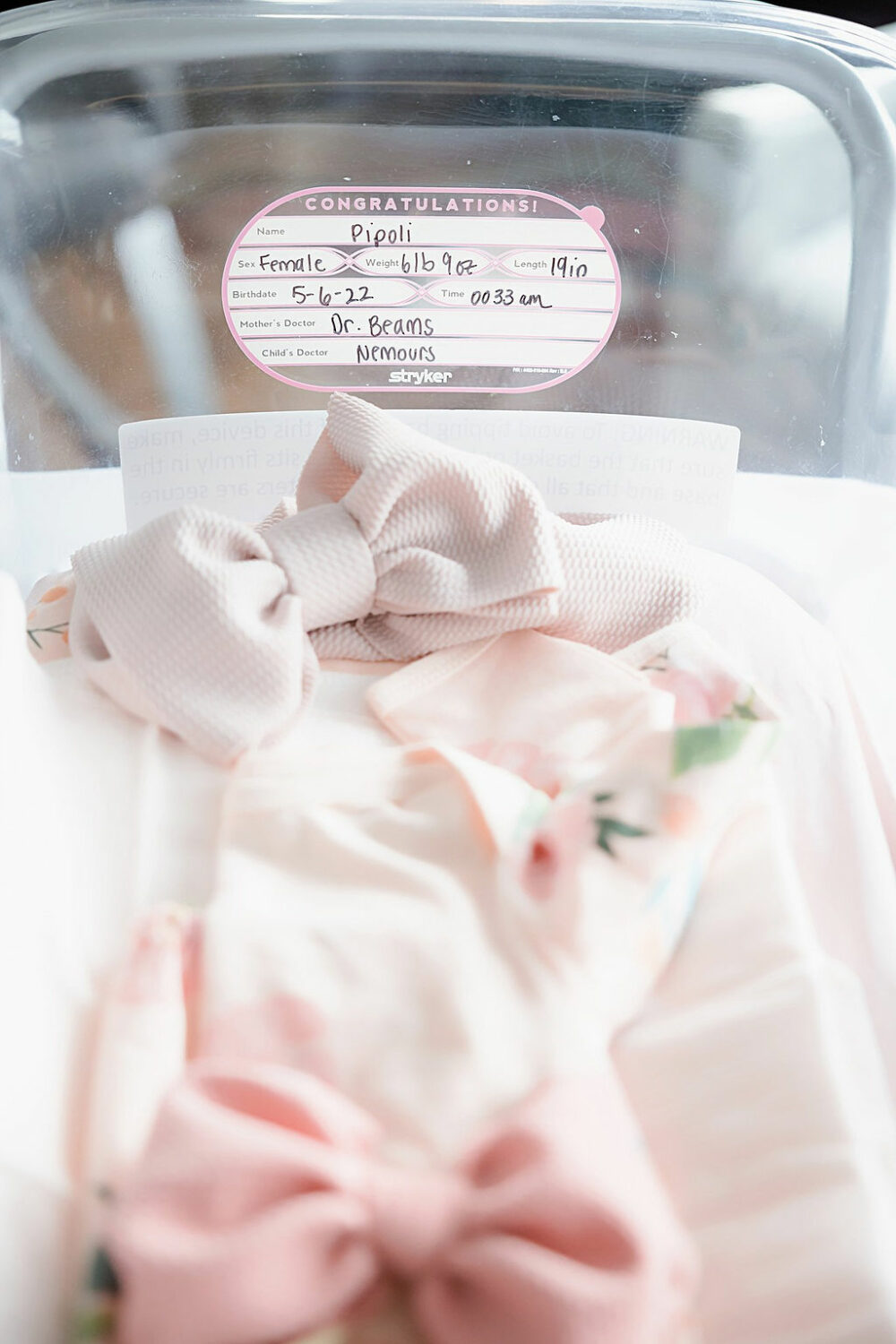 Baby stats and newborn outfits in bassinet for a springtime fresh 48 session in Cinnaminson, New Jersey.