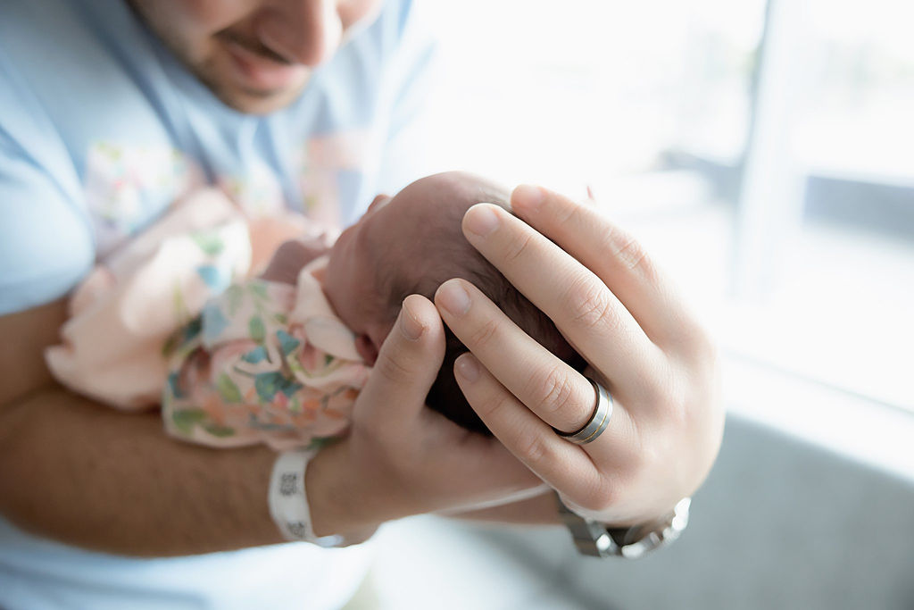 Dad holding newborn in arms for her in-hospital fresh 48 session in Cherry Hill, New Jersey.