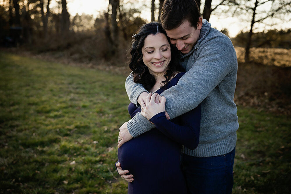 Pregnant women being held by husband for their baby bump photography session in Jersey City, New Jersey.