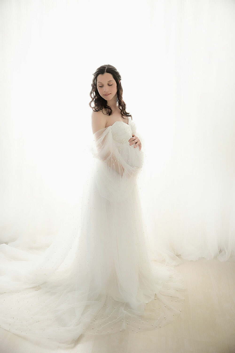 Pregnant woman holding belly and maternity dress for her professional maternity pictures in Toms River, New Jersey.