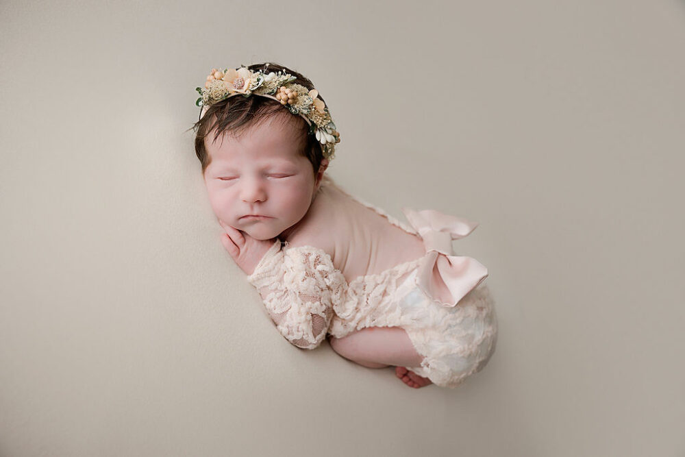 Newborn girl sleeping on tummy with headband and newborn outfit for her professional newborn session in Medford, New Jersey.