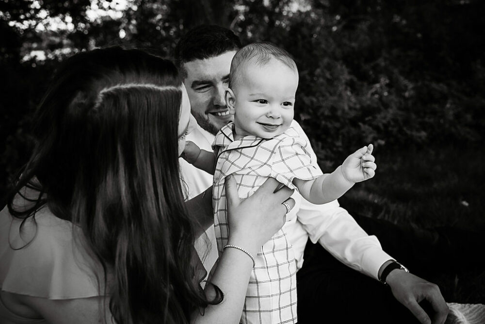 Mom and dad holding young son for their summer fun outdoor family session in Cherry Hill, New Jersey.