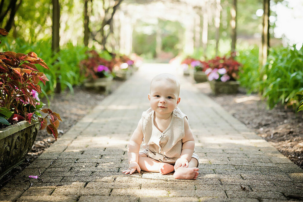 Baby boy sitting on stone walkway for a summer fun outdoor family session in Newark, New Jersey.
