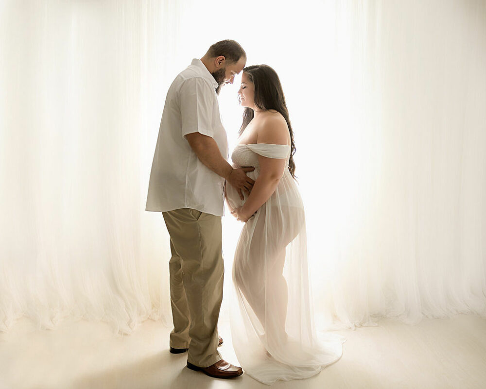 Couple holding belly for their their light and radiant maternity session in South Jersey.