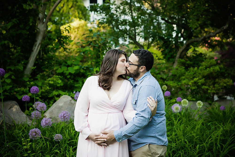 Husband and wife kissing for their professional pregnant couple photo shoot for their spiring garden maternity session in Mount laurel, New Jersey.