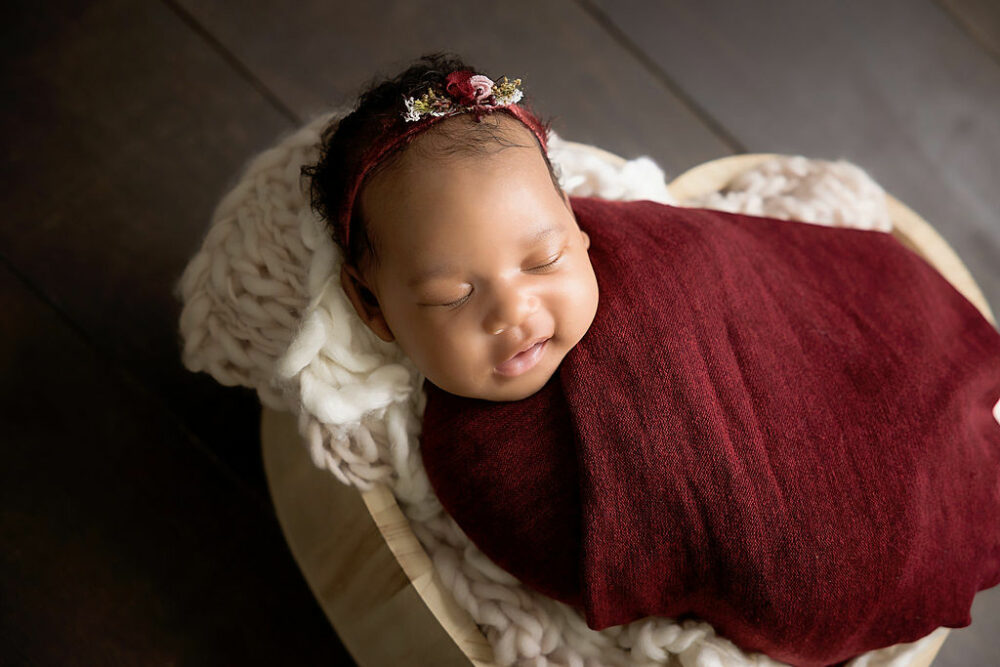 A newborn girl in swaddle on heart photography props for her newborn session and Haddonfield, NJ.