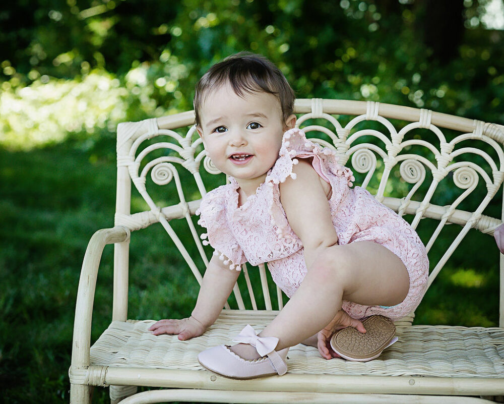 Close up of toddler girl sitting on outdoor chair for her pink first birthday session In Cherry Hill, New Jersey.