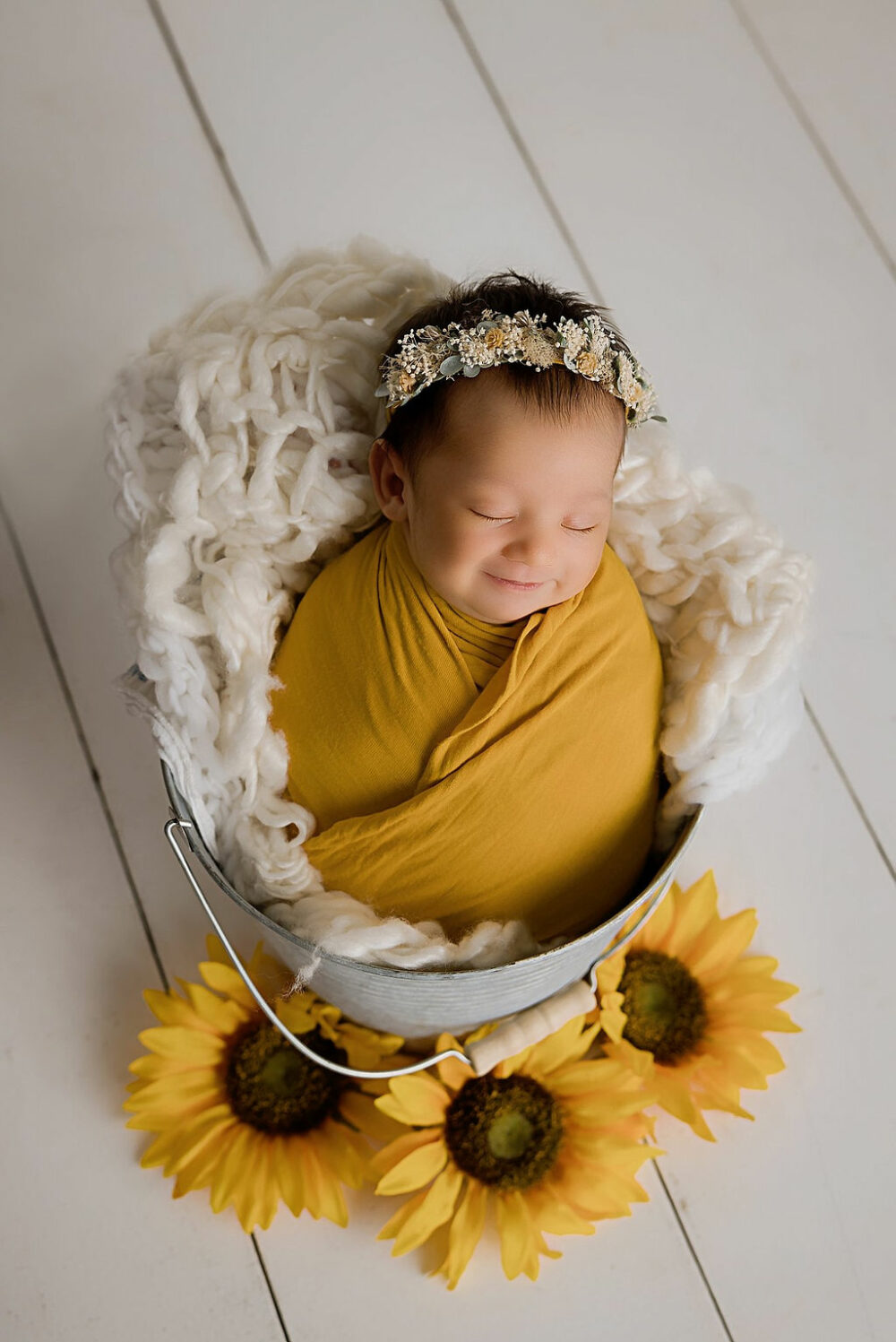 Newborn portrait of girls, sleeping in bucket, photography prop with sunflowers for her yellow In-studio newborn session in Princeton, New Jersey.