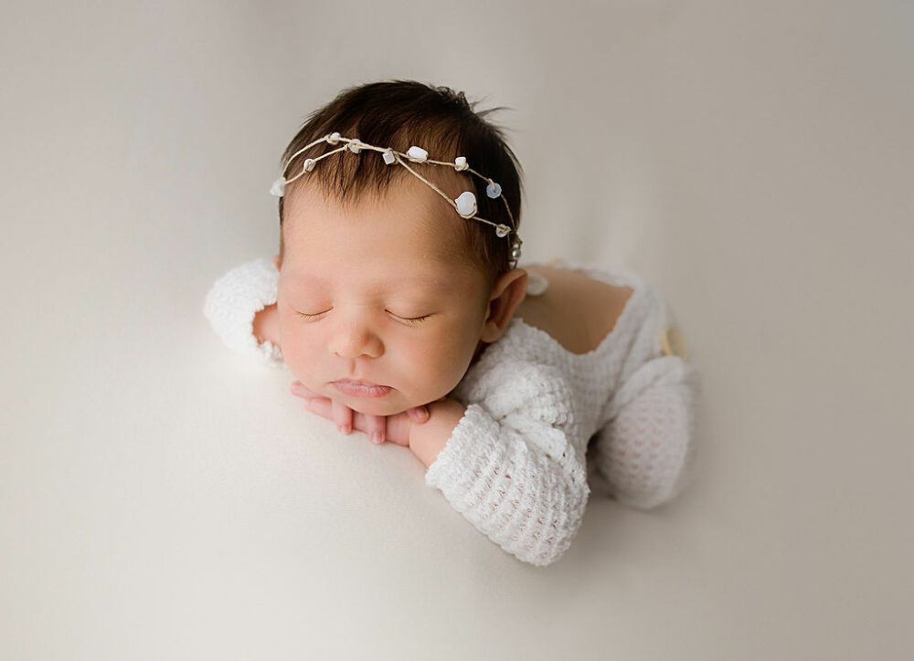 Newborn girl, resting head on hands, sleeping for her newborn photography poses Taken in studio In Lindenwold, NJ.