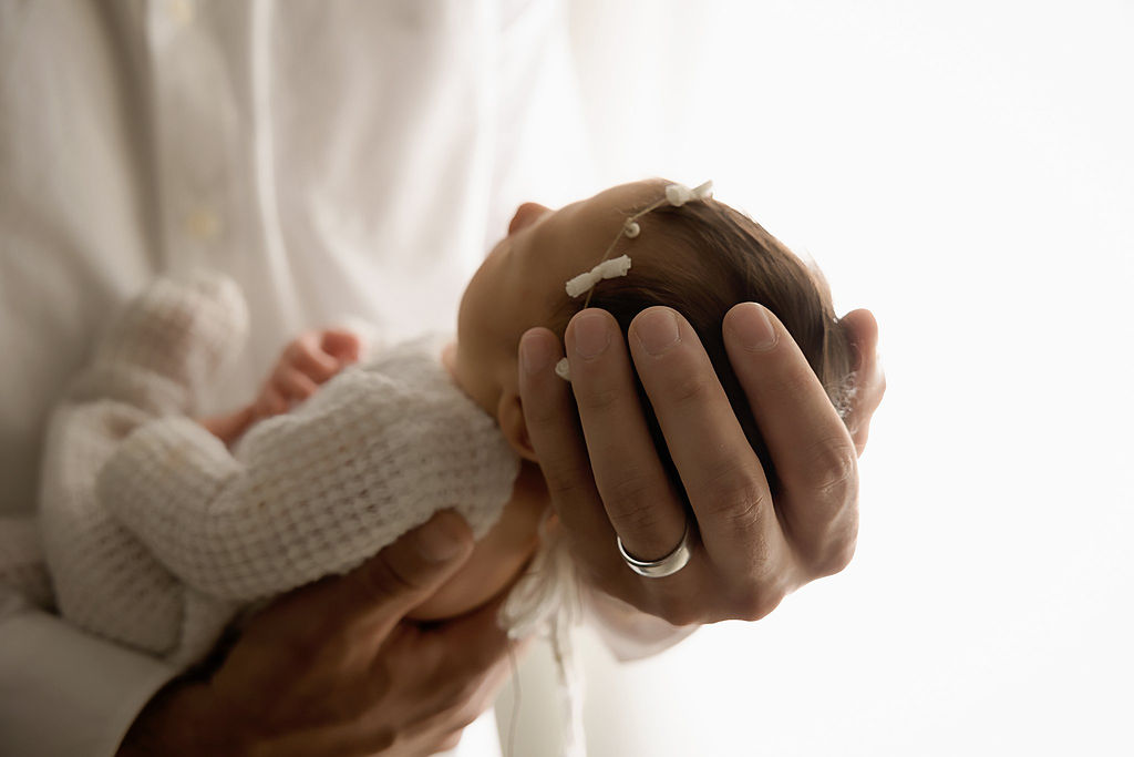 Close up of newborn girl, sleeping in her father’s hands for their in-studio newborn session in Bordentown, New Jersey.