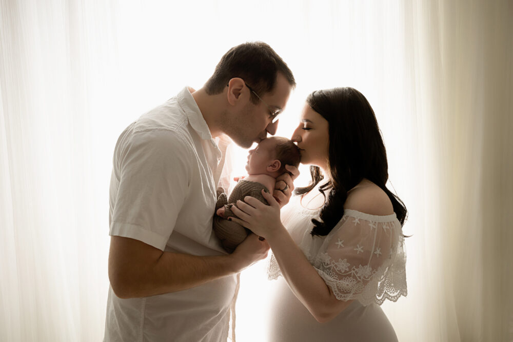 south jersey newborn photo shoot with mom and dad kissing baby