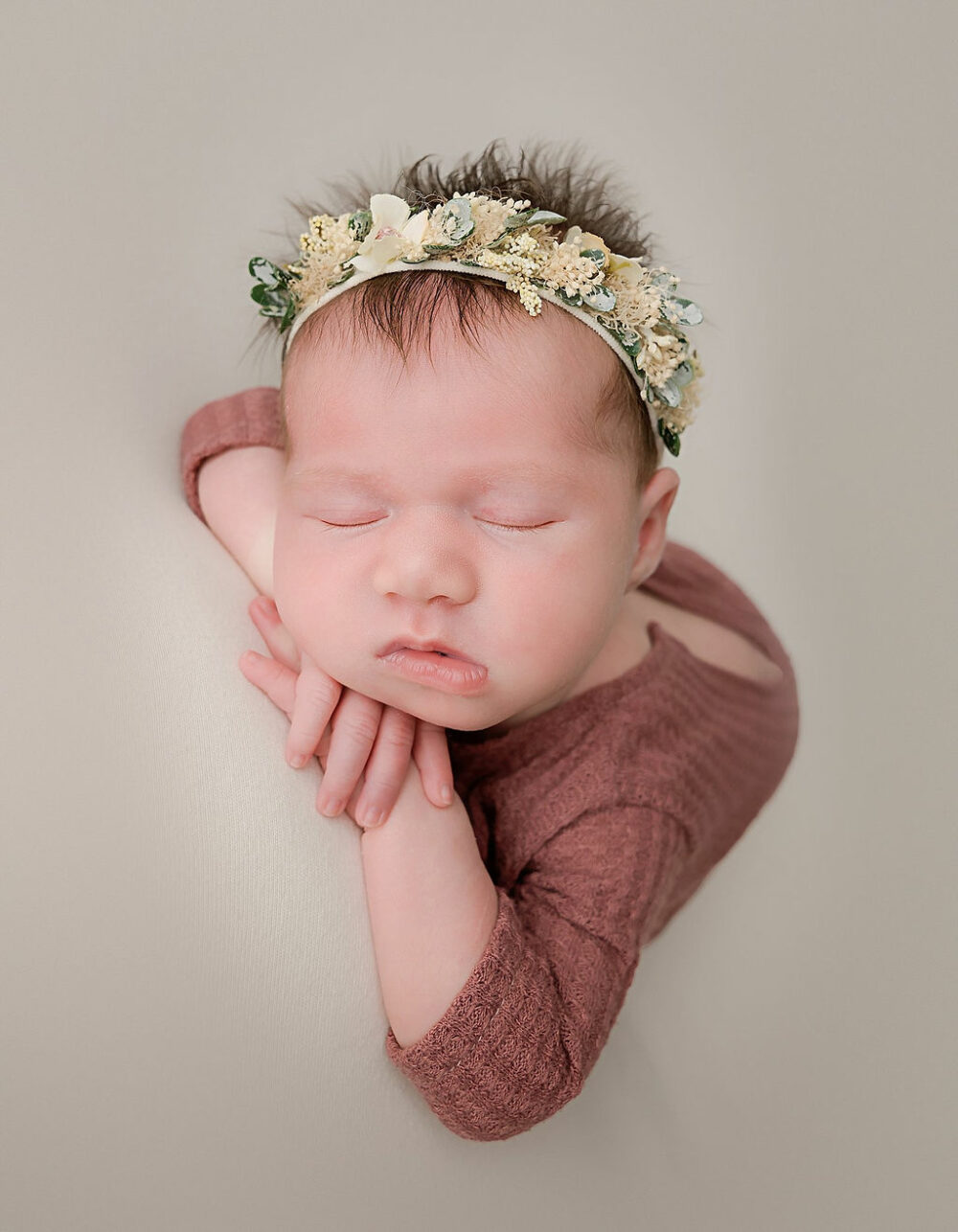 Close up of sleeping infant girl in newborn outfit wearing flowery headband for her summer newborn session in Pemberton, New Jersey.