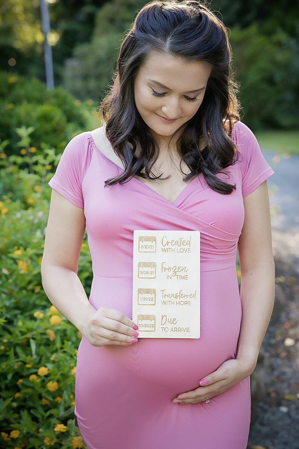 Close-up of pregnant woman holding wooden mile stone prop while holding belly for her mile stone maternity and newborn session in Southampton, New Jersey.