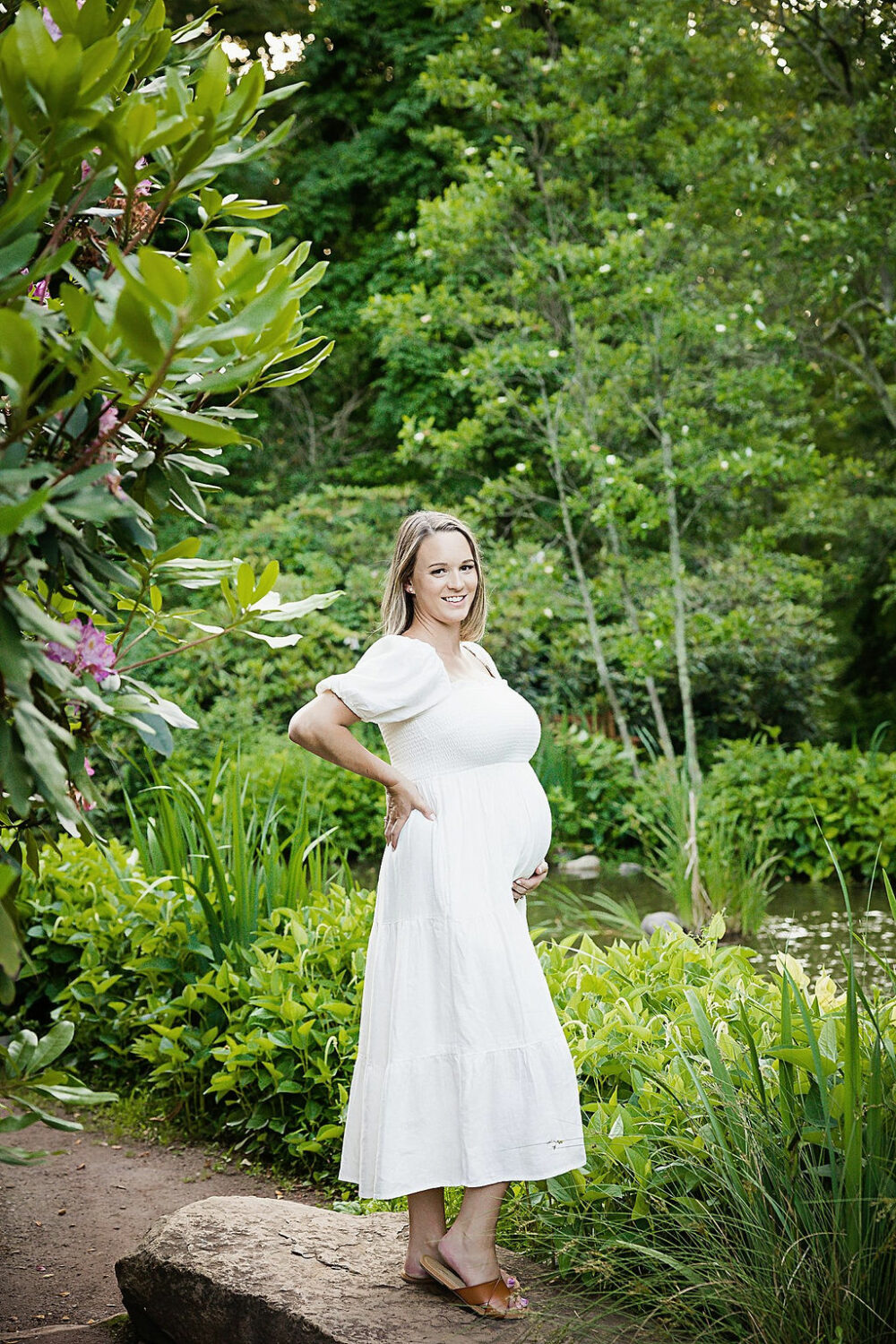 Pregnant woman smiling at camera doing maternity photo shoot poses for her maternity session in Millstone, New Jersey.