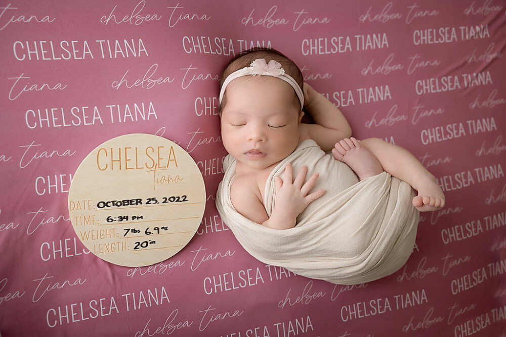 Sleeping newborn girl laying on Caden lane personalized blanket next to Wood personalized name for her milestone newborn session in East Hampton, New Jersey.