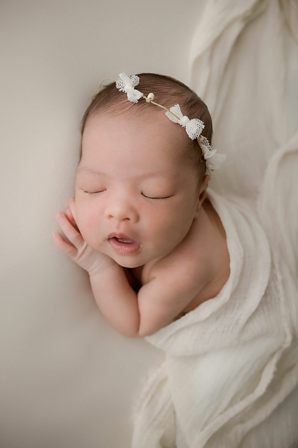 Newborn girl laying head on her hand sleeping with her mouth open for her newborn photography session in Hainesport, New Jersey.