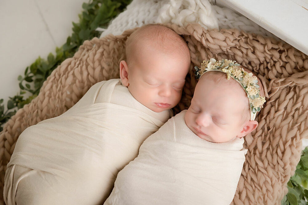 Twin newborn boy, and a girl, both sleeping on textured blanket in newborn photography prop for their twin neutral newborn session, taken in Southampton, New Jersey.