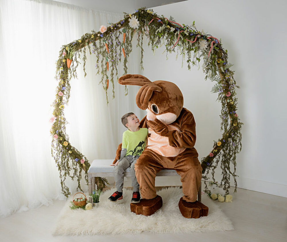 Young boy sitting next to Easter bunny for in studio Easter mini session in Mount Holly, New Jersey.