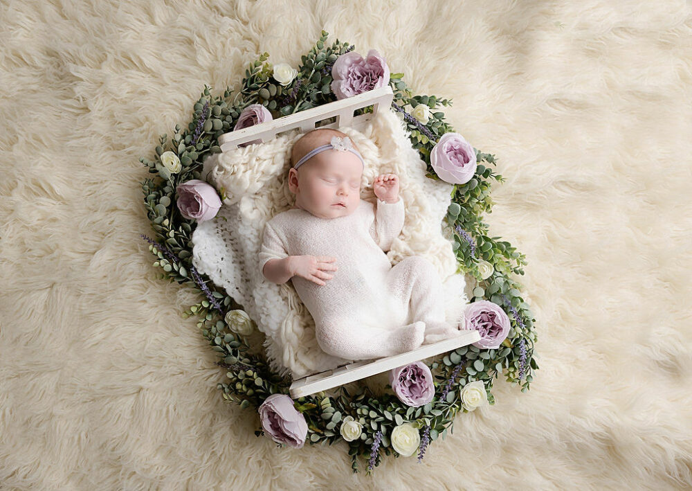Aerial photo of a sleeping newborn girl, sleeping on textured, blankets and crib, photography prop for her purple in Home newborn session, taken in Burlington, New Jersey.