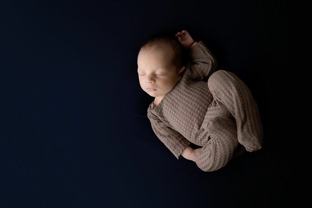 Newborn boy sleeping on beanbag with newborn outfit for his professional newborn session taken in Moorestown, New Jersey.