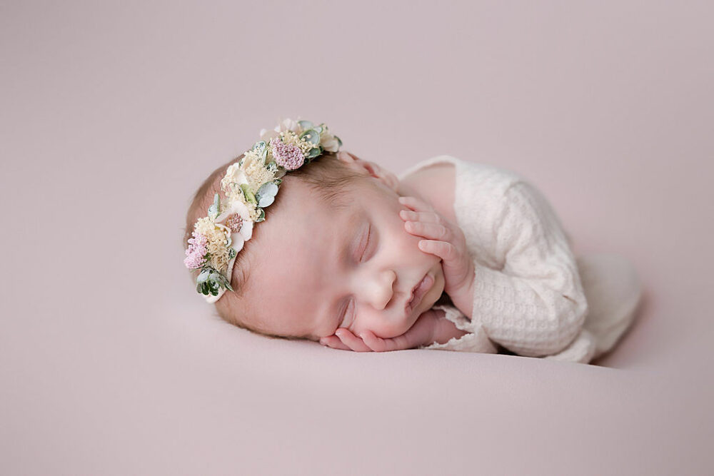 Infant girl, sleeping on her side, with hand on her cheeks, for her pink newborn session, taken in Hamilton, New Jersey.