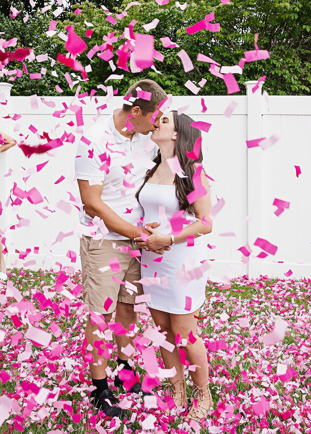 Man and woman standing in backyard with confetti around them, kissing for their gender reveal photo, shoot in Moorestown, New Jersey.