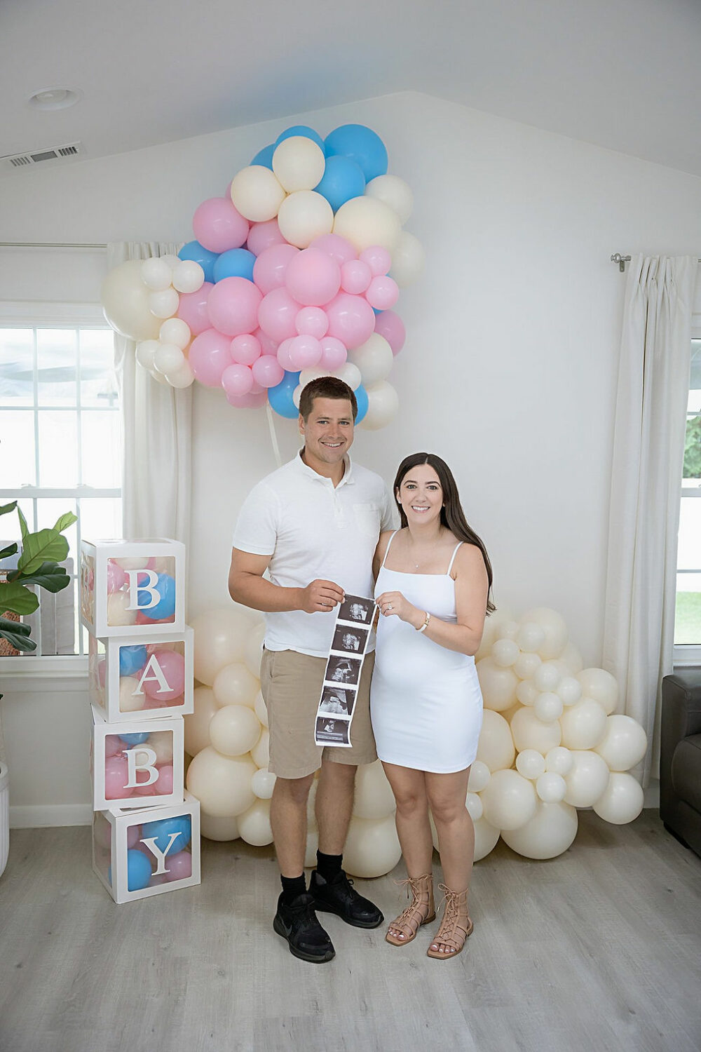Man and woman standing next to each other, holding ultrasound, photos taken during their gender reveal photo session in Eastampton, New Jersey.