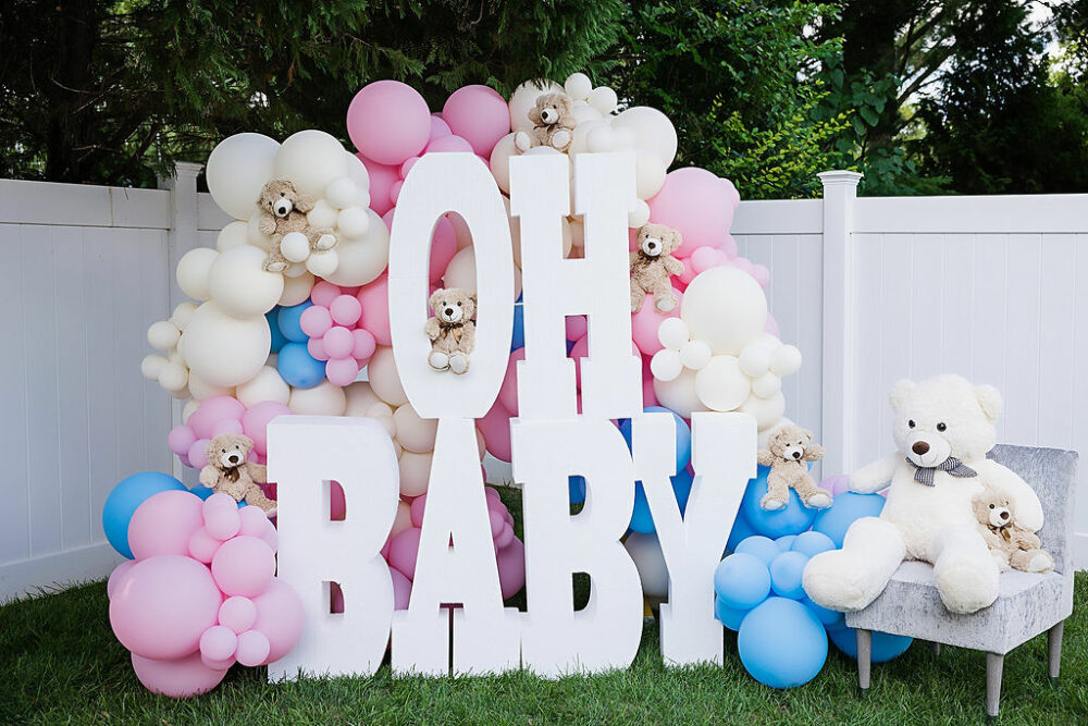 A large gender reveal sign, adorned with balloons and teddy bears placed outside for an in-Home gender reveal photo session in Pemberton, New Jersey.