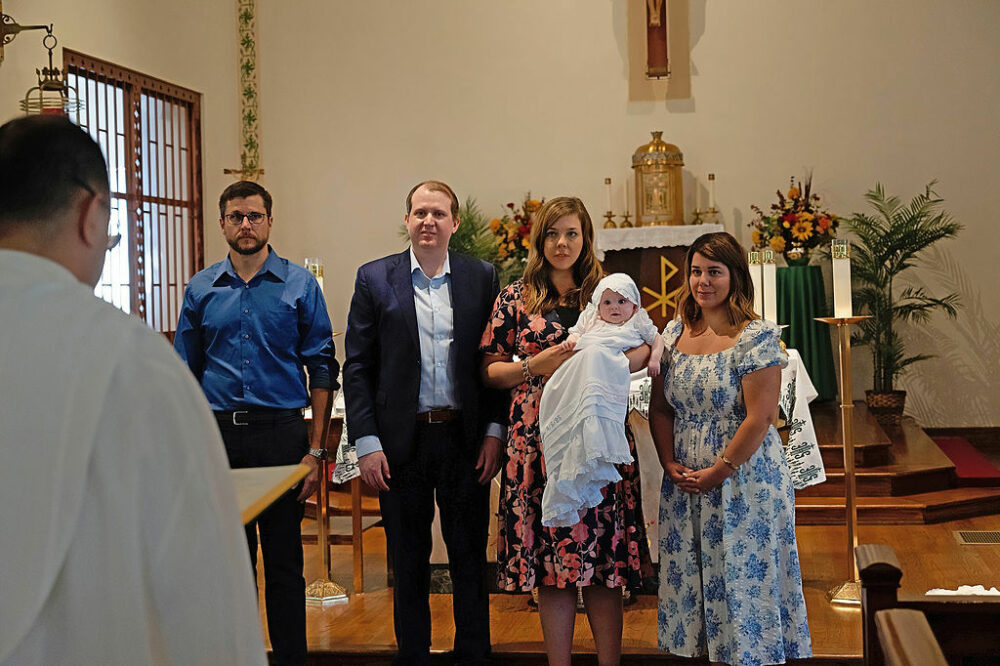 Candid photo of parents and godparents listening to sermon given by their church pastor for their daughters baby baptism and family session taken in Cherry Hill, NJ.